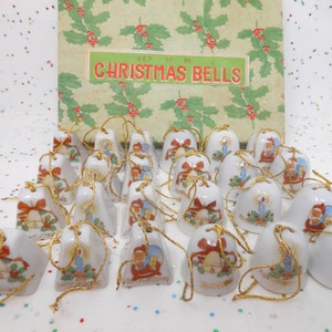 May include: A set of 24 Christmas bells. The white ceramic bells have gold string hangers and are decorated with images of Santa Claus, candles, and bells with red bows. The box behind the bells reads "Set of 24 Christmas Bells".