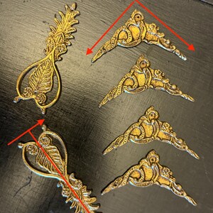 May include: Gold-coloured metal decorative embellishments with intricate designs. The largest piece measures 10.5 x 4cm, and the corner pieces are 6.5 x 6.5cm. These ornate pieces are suitable for various craft projects.