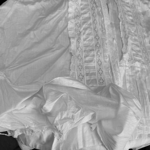 May include: A white, ruffled, and lacy skirt with a delicate, intricate pattern. The skirt is made of a soft, flowing fabric and has a vintage aesthetic.