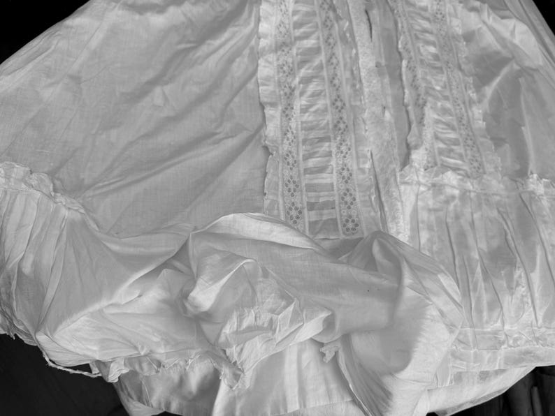 May include: A white, ruffled, and lacy skirt with a delicate, intricate pattern. The skirt is made of a soft, flowing fabric and has a vintage aesthetic.