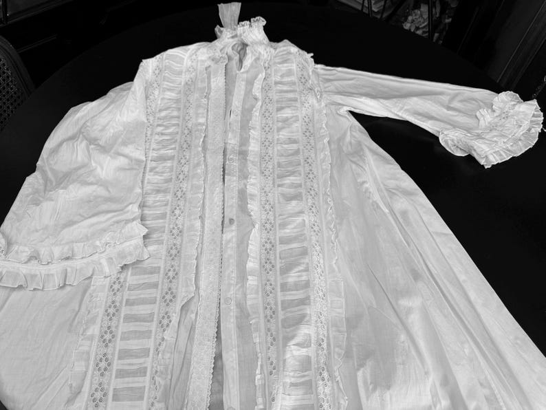 May include: A white cotton robe with lace trim and ruffles. The robe has a long, flowing silhouette and is perfect for lounging around the house.