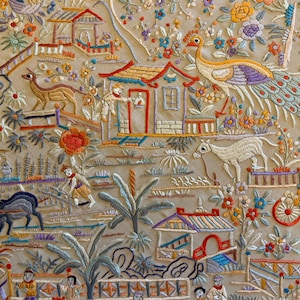 May include: Detailed embroidery depicting a pastoral scene with figures, animals, and buildings. The artwork features a variety of colors, including red, blue, yellow, and green, creating a vibrant and intricate design. The scene includes a peacock, houses, and people.