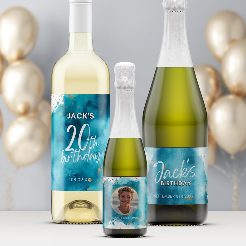 May include: Three bottles of sparkling wine with personalized labels for a 20th birthday. The labels feature a blue watercolor background with gold accents and the text "Jack's 20th birthday". One bottle has a photo of a person on the label.