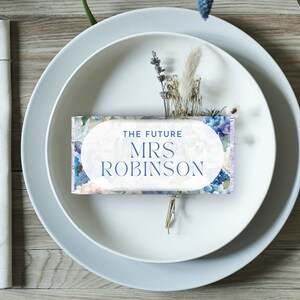 Peut inclure: Une carte de table florale bleue et blanche avec le texte "The Future Mrs. Robinson".