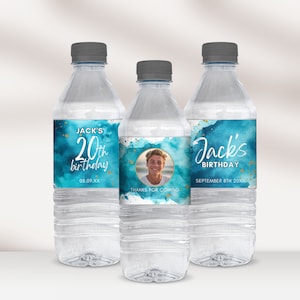 May include: Three clear plastic water bottles with blue and gold labels. The labels feature a watercolor design with gold glitter accents. The labels also include the text "Jack's 20th birthday" and a photo of a young man.