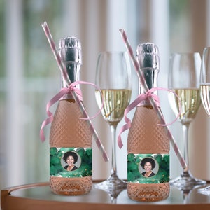 Op de afbeelding: Twee mini-flessen mousserende wijn met gepersonaliseerde etiketten. De etiketten hebben een groene aquarel achtergrond met gouden accenten en een foto van een persoon. De tekst op de etiketten luidt "Bedankt voor je komst".