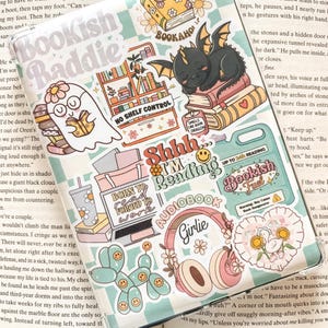May include: A collection of colourful stickers featuring various bookish themes. The stickers include a ghost reading a book, a dragon sleeping on a stack of books, a laptop with the text "Born to read, forced to work", a pair of headphones with the text "Girlie", a balloon dog with smiley faces, and a bookish fuel sticker with the text "Shhh I'm reading audiobook".