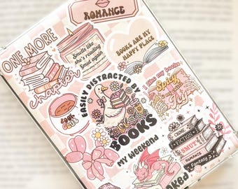 May include: A clear phone case decorated with pink and white stickers. The stickers feature book-related themes, including stacks of books, a candle, a duck, and the words "Romance," "Books," and "Smut." The case has a pink checkered background.