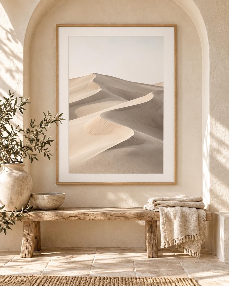 May include: A framed vertical wall art print featuring a desert landscape with rolling sand dunes in shades of beige, tan, and soft gray. The image displays a clear horizon line under a pale sky, captured with high contrast between light and shadow.