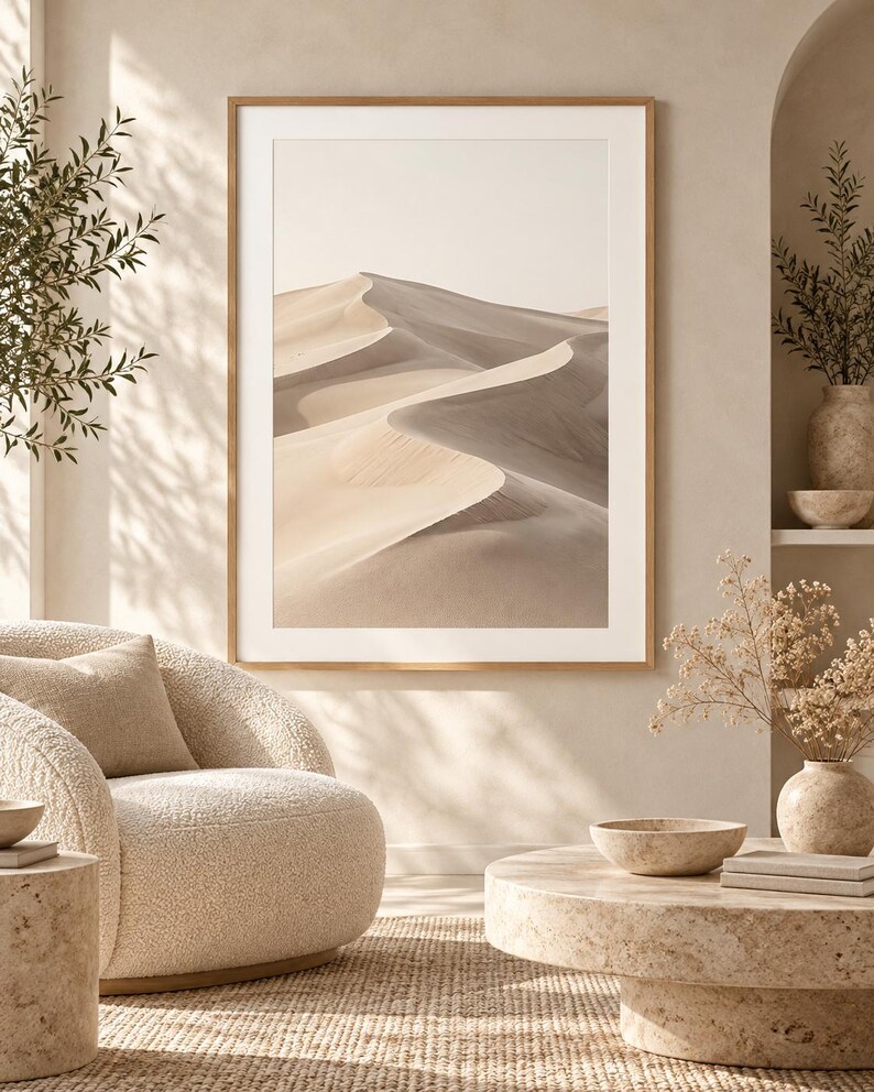 May include: A framed vertical wall art print featuring a desert landscape with rolling sand dunes in shades of beige, tan, and soft gray, displayed in a light wood frame with a wide white mat border.