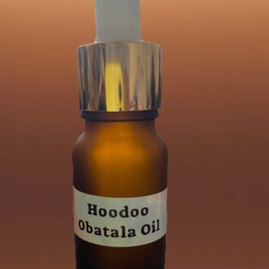 May include: A brown glass bottle with a white label that reads "Hoodoo Obatala Oil." The bottle has a silver and white dropper top. The oil inside the bottle is visible.