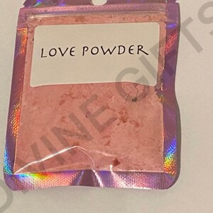 May include: A small, iridescent pink pouch with a white label that reads "LOVE POWDER".