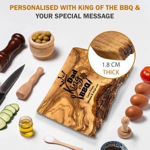 Puede incluir: Una tabla de cortar de madera con el texto "Dad King of the BBQ!" y un gr&aacute;fico de corona. La tabla tiene 1,8 cm de grosor y est&aacute; rodeada de ingredientes y utensilios de cocina, como aceitunas, huevos y un cuchillo.