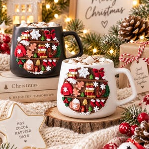 Könnte beinhalten: Ein schwarzer und ein weißer Keramikbecher, jeweils mit einem kreisförmigen Reliefdesign eines Holzregals, das mit weihnachtlichen Miniaturartikeln wie Lebkuchenmännern, roten Pullovern, Geschenken und Schneeflocken gefüllt ist.