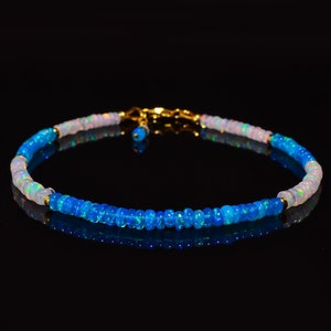 May include: A delicate bracelet made with blue and white opal beads. The bracelet has a gold clasp and is perfect for adding a touch of elegance to any outfit.