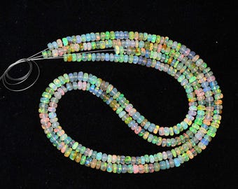 May include: A strand of multi-colored opal beads. The beads are small and round, and they are strung on a wire. The beads are a variety of colors, including green, blue, pink, and white.