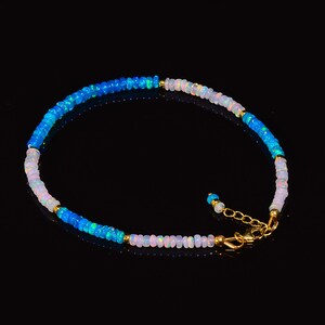 May include: A delicate anklet made with small, round opal beads in shades of blue and white. The anklet has a gold clasp.