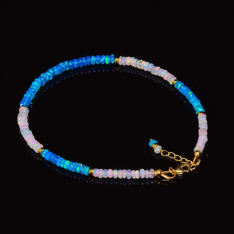 May include: A delicate anklet made with small, round opal beads in shades of blue and white. The anklet has a gold clasp.