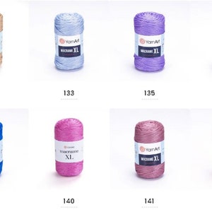 May include: Assortment of ten spools of macrame cord in various colors, including beige, light blue, purple, cream, blue, pink, mauve, and yellow. Each spool is labeled "YarnArt Macrame XL".