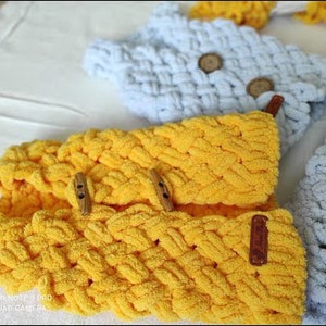 Puede incluir: Tres diademas de tejido de punto en amarillo y azul claro con detalles de botones de madera. Las diademas est&aacute;n hechas con un patr&oacute;n de punto trenzado.