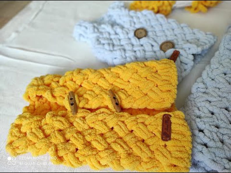 Puede incluir: Tres diademas de tejido de punto en amarillo y azul claro con detalles de botones de madera. Las diademas est&aacute;n hechas con un patr&oacute;n de punto trenzado.