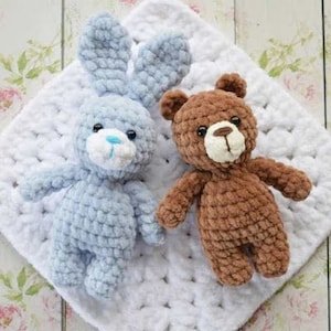 Puede incluir: Un conejito de crochet azul y un osito de crochet marr&oacute;n sobre una manta de crochet blanca.