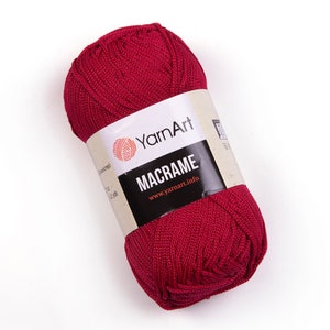 May include: A ball of deep red yarn labeled "YarnArt Macrame" with the website address "www.yarnart.info" printed on the label.