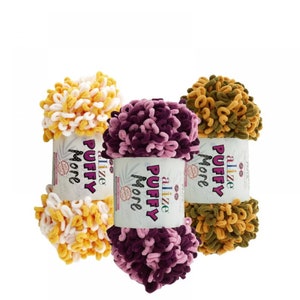 May include: Three skeins of yarn in different colors: yellow and white, purple and pink, and green and brown. The yarn is fluffy and textured. The label on each skein reads "Alize Puffy More".