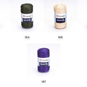 May include: Five spools of yarn in different colors: red, green, beige, light brown, and purple. Each spool has a label that says "YarnArt Macrame XL".