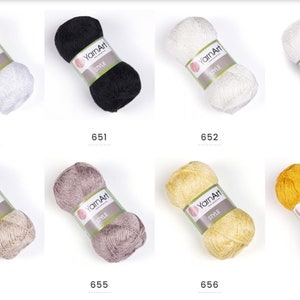 Pode incluir: Uma cole&ccedil;&atilde;o de dez novelos de fio em v&aacute;rias cores, incluindo branco, preto, bege, cinza, amarelo e dourado. Cada novelo &eacute; etiquetado com "YarnArt" e tem um n&uacute;mero de 650 a 657.