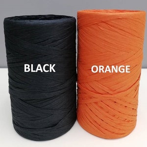 May include: Two spools of paper raffia, one black and one orange. The spools are labeled "BLACK" and "ORANGE".
