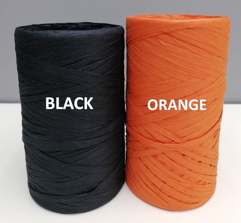 May include: Two spools of paper raffia, one black and one orange. The spools are labeled "BLACK" and "ORANGE".