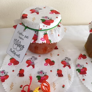 Peut inclure: Un pot en verre de confiture multifruits faite maison avec un couvercle en tissu blanc à imprimé souris. Le pot est étiqueté "Confiture faite maison Multifruits".