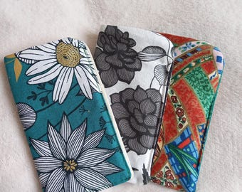 May include: Three fabric pouches with different floral patterns. The pouches are teal, white, and red with black and white floral designs.