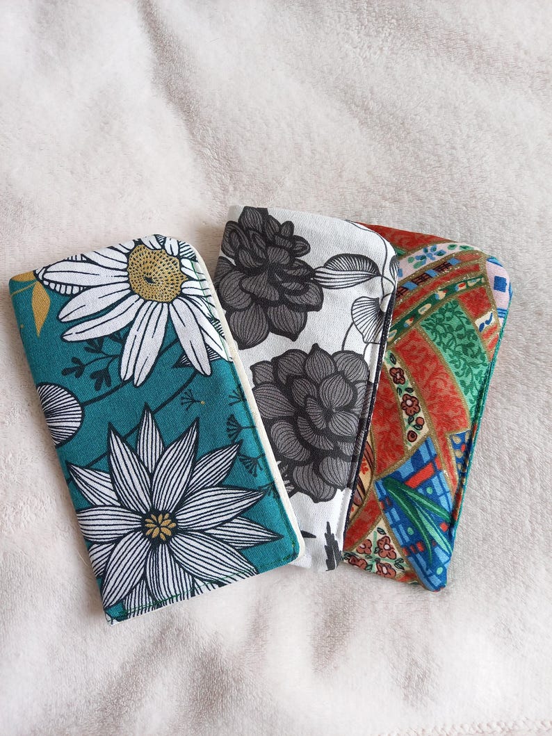 May include: Three fabric pouches with different floral patterns. The pouches are teal, white, and red with black and white floral designs.