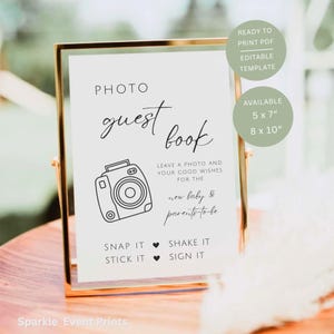 May include: A framed sign with the words "PHOTO guest book" in elegant script. Below, a camera illustration and text: "Leave a photo and your good wishes for the new baby & parents-to-be." Available in 12.7 x 17.8 cm and 20.3 x 25.4 cm sizes.