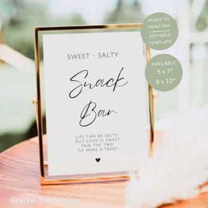 Könnte beinhalten: Ein goldgerahmtes Schild mit den Worten "SWEET • SALTY" und "Snack Bar" in eleganter Schrift. Das Schild enthält den Text "LIFE CAN BE SALTY, BUT LOVE IS SWEET. PAIR THE TWO TO MAKE A TREAT!" und ist in den Größen 12,7 x 17,8 cm und 20,3 x 25,4 cm erhältlich.