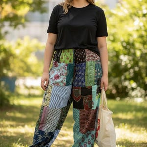 May include: A person wearing a black t-shirt and patchwork pants with various patterns and colors, including floral and striped designs. The person is also wearing white sneakers and carrying a canvas tote bag.