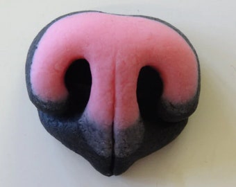 Könnte beinhalten: Nahaufnahme einer Hundenase mit rosa Mitte und schwarzen Außenkanten. Die Nase hat zwei Nasenlöcher und eine strukturierte Oberfläche. Die Form ist symmetrisch und abgerundet.