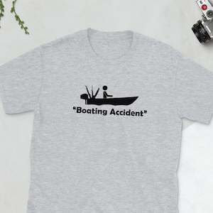 May include: A grey t-shirt with a black graphic of a person in a boat with the text "Boating Accident".