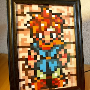 May include: Framed pixel art of a video game character with red hair, a blue shirt, and brown pants. The character is standing on a brown background.