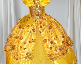 May include: A yellow princess dress with a gold bodice, a large yellow bow, and a gold crown. The dress has a tulle skirt with gold glitter and a satin overlay.
