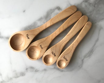 Könnte beinhalten: Satz mit vier Messlöffeln aus Holz mit folgenden Maßen: 1/4 TL, 1/2 TL, 1 TL und 1 EL.