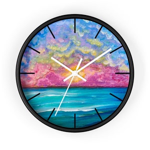 May include: A round clock with a black frame and white hands. The clock face features a colourful painting of a sunset over the ocean with pink, blue, and yellow hues.