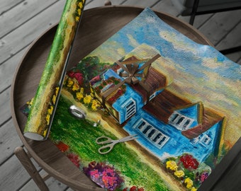 May include: A blue house with a brown roof is painted on a wrapping paper with a green lawn, flowers, and a blue sky. The house has white windows and a brown door. A brown ribbon is tied around a smaller box in front of the house.