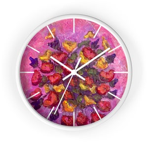 May include: White-framed wall clock with a floral design. The clock face features a vibrant, impressionistic painting of red, yellow, and purple flowers against a pink background. White hands and hour markers complete the design.