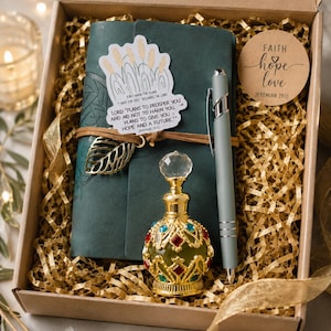 May include: A gift box containing a dark green leather journal with a leaf charm, a gray ballpoint pen, and an ornate glass perfume bottle with gold accents and red and blue gems. A sticker on the journal reads: Plans to prosper you, Jeremiah 29:11.