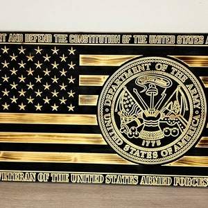 Puede incluir: Un letrero de madera con fondo negro y letras doradas. El letrero presenta una bandera estadounidense con un patrón de estrellas doradas y el sello del ejército de los Estados Unidos. El texto en el letrero dice "SUPPORT AND DEFEND THE CONSTITUTION OF THE UNITED STATES AGAINST ALL ENEMIES, FOREIGN AND DOMESTIC. I DO SOLEMNLY SWEAR THAT I WILL... VETERAN OF THE UNITED STATES ARMED FORCES".