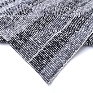 Könnte beinhalten: Nahaufnahme eines schwarz-weiß gestreiften Teppichs mit Fransenkante. Der Teppich ist in der Mitte gefaltet und zeigt die Textur des Stoffes.
