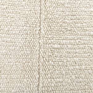 May include: Close-up of a white, fluffy, textured fabric. The fabric has a subtle, woven pattern.